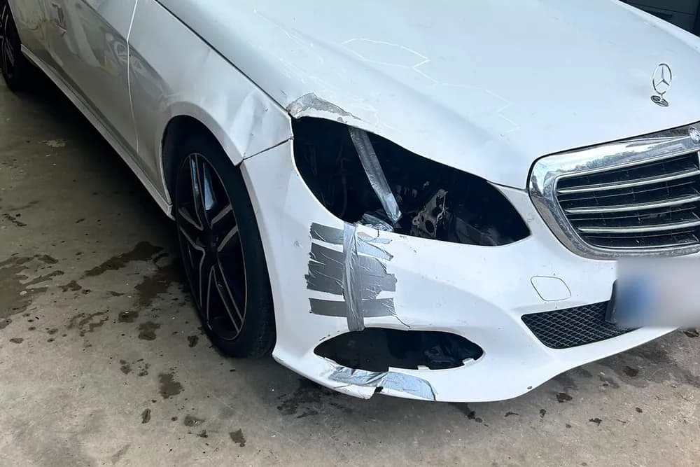 Kolarissa vaurioitunut valkoinen Mercedes, jonka etulokasuoja ja puskuri ovat rikki